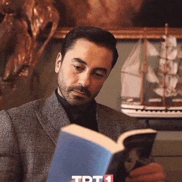 a man in a suit is reading a book with tpt1 on the bottom right