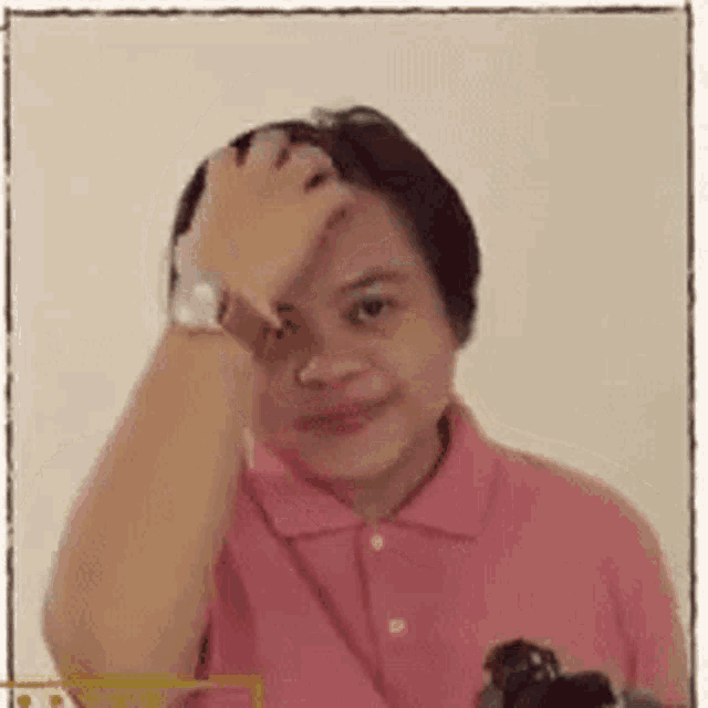 a woman in a pink shirt is scratching her forehead while wearing a watch .
