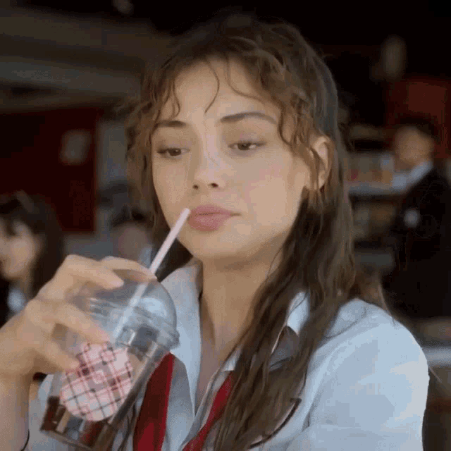 a woman drinking from a cup with a straw