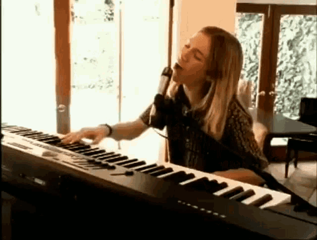 a woman is singing into a microphone while playing a keyboard .
