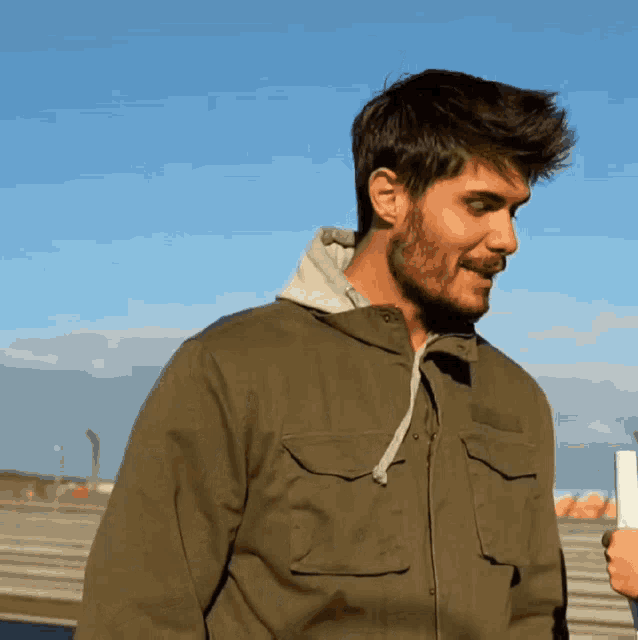 a man with a beard wearing a green jacket with pockets