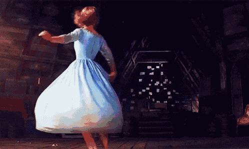 a woman in a blue dress is dancing in the dark