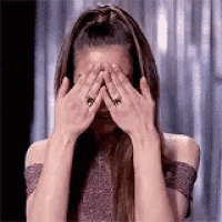 a woman is covering her face with her hands and wearing a ring .