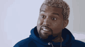 kanye west is wearing headphones and a blue hoodie and looking at the camera .