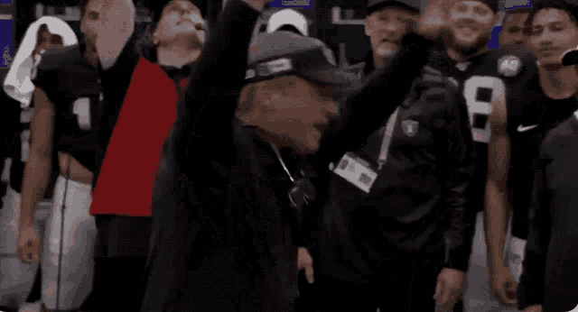 a man wearing a raiders shirt is dancing in front of a group of people