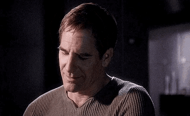 a close up of a man 's face with his eyes closed and a sweater on .
