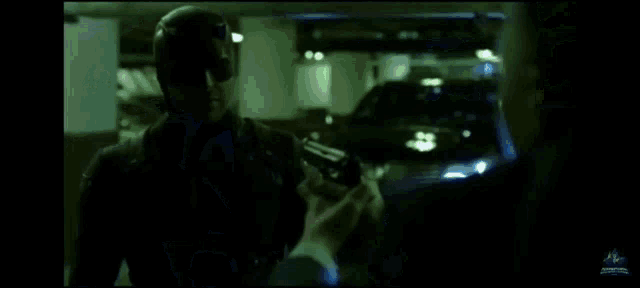 a man is laying on the ground in a parking garage while a police officer holds him up .