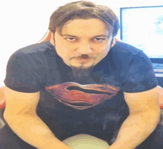 a man with a beard is wearing a black shirt with a superman logo on it