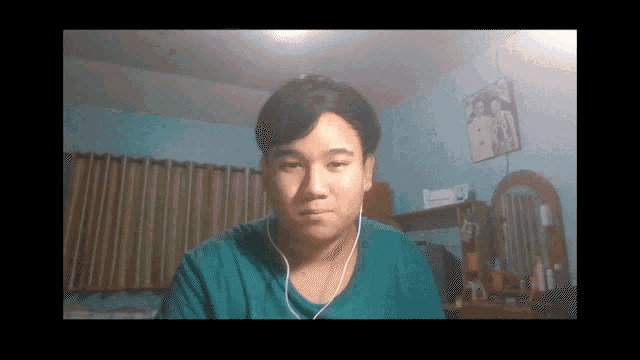 a man wearing earbuds looks at the camera in a room