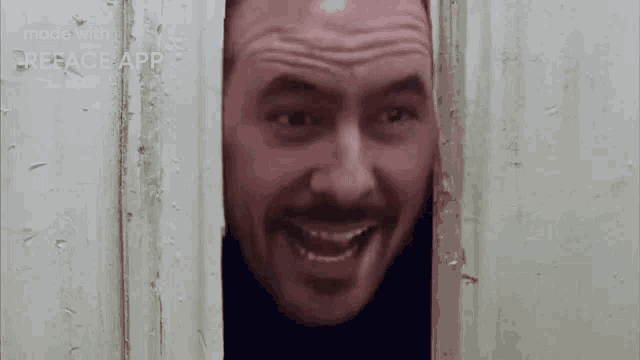 a man with a beard is peeking out of a doorway .