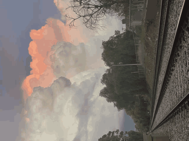 a train track with a cloudy sky and a rainbow in the background