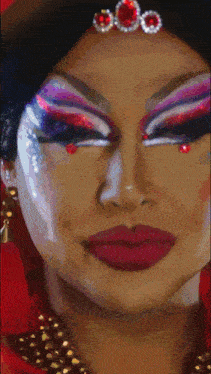 a close up of a drag queen 's face with a crown on her head