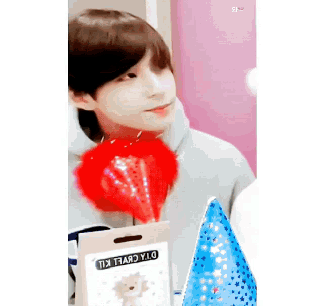 a young boy is holding a red balloon and a party hat .