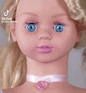 a doll head with blonde hair and blue eyes is sitting on top of a metal table .