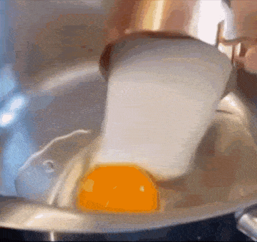a close up of an egg being cracked into a pot of water .