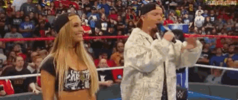a man is standing next to a woman in a wrestling ring while holding a microphone .
