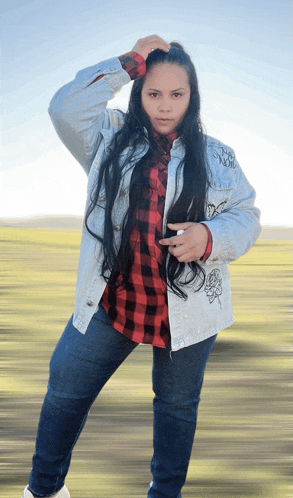 a woman wearing a plaid shirt and a denim jacket has the word no on her jacket