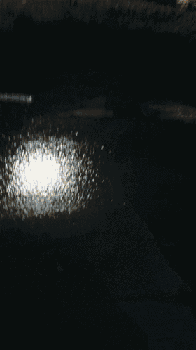 a person 's hand is reaching for something on a dark surface