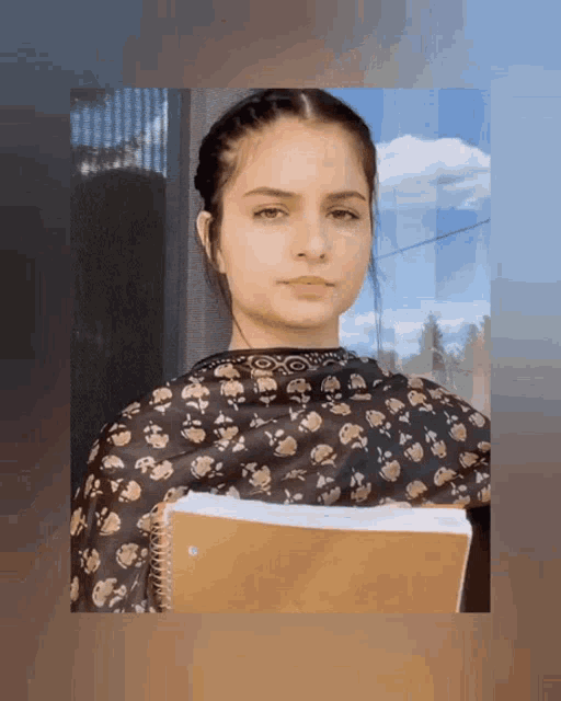 a girl in a floral dress holds a notebook