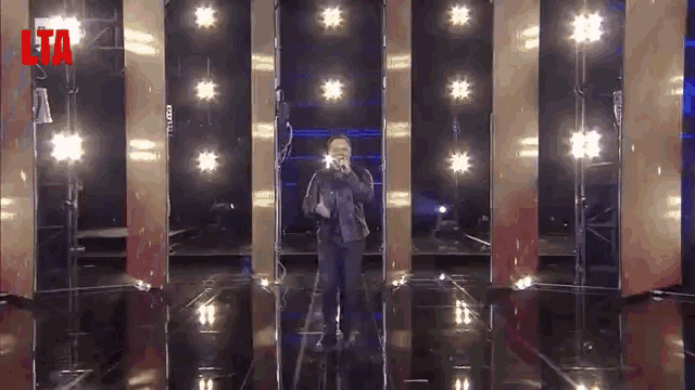 a man is singing into a microphone on a stage with the word lta on the bottom
