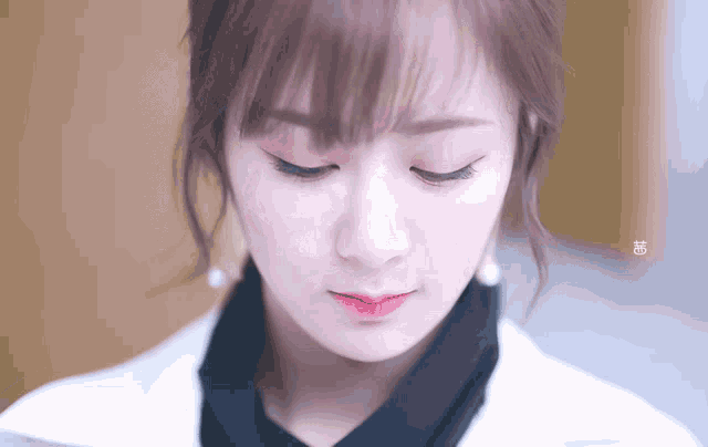 a close up of a woman 's face with her eyes closed and the letter g on the bottom left