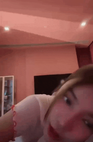 a woman is laying on a bed in a pink room with a pink ceiling .