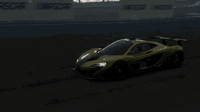 a yellow and green sports car is driving on a race track at night