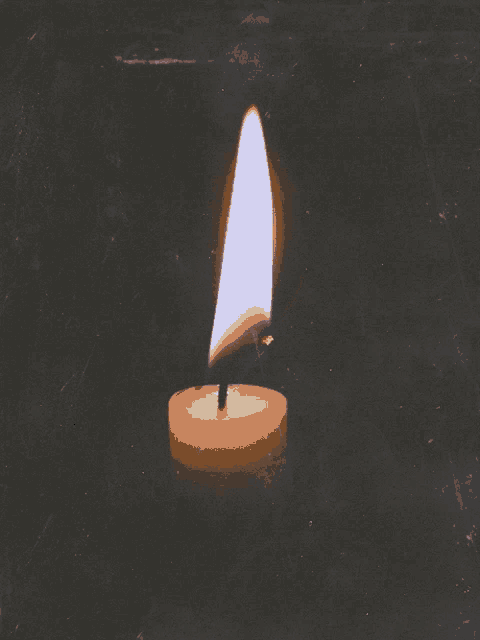 a candle is lit up in the dark and the flame is visible