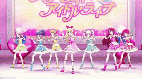 a group of anime girls are standing next to each other on a stage in front of a sign .