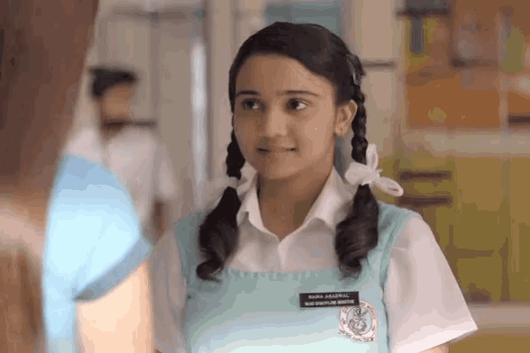 a girl in a school uniform has a name tag that says sneha aashwar