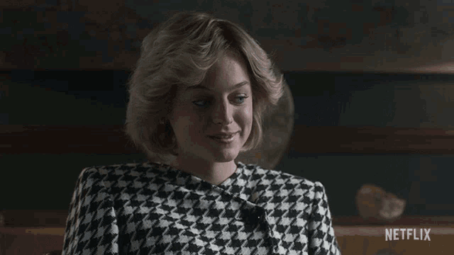 a woman wearing a black and white houndstooth jacket is sitting in front of a netflix sign