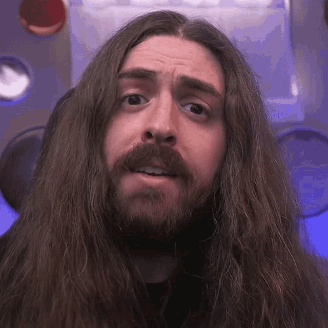 a man with long hair and a beard is looking at the camera