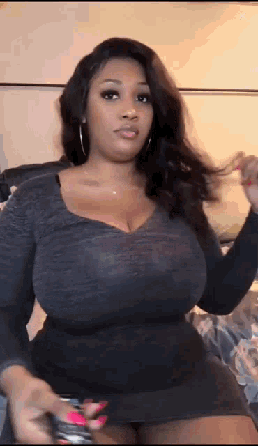 a woman with very large breasts is wearing a black dress and earrings