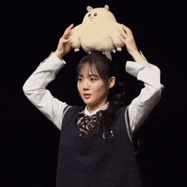 a girl with a stuffed animal on her head with the letter c on the vest