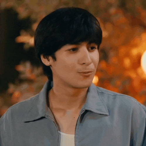a young man wearing a blue jacket is making a face