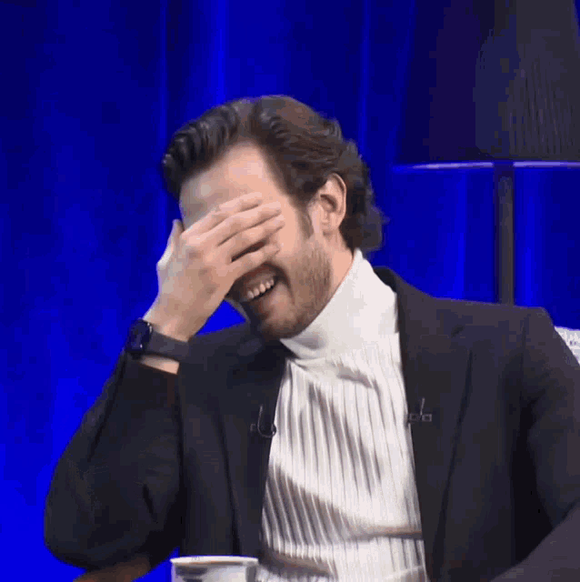 a man wearing a turtleneck and a suit is smiling