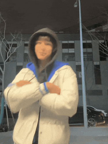 a person with their arms crossed wearing a white jacket and a hoodie