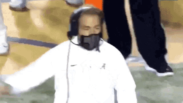 a man wearing a nike sweatshirt and headphones stands on a field
