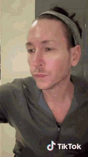 a man with a headband on his head has a tiktok logo on the bottom of his face