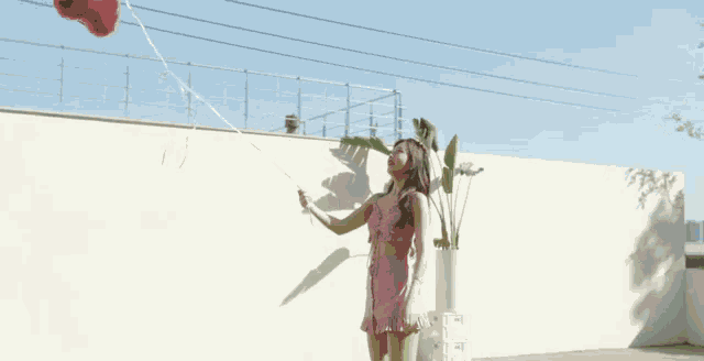 a woman in a pink dress holding a red balloon