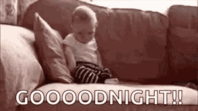 a baby is sitting on a couch with the words `` good night '' written on it .