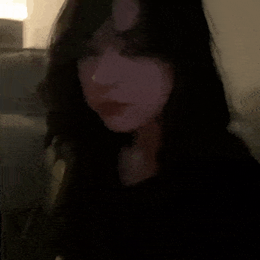 a close up of a woman 's face in a dark room with her eyes closed .