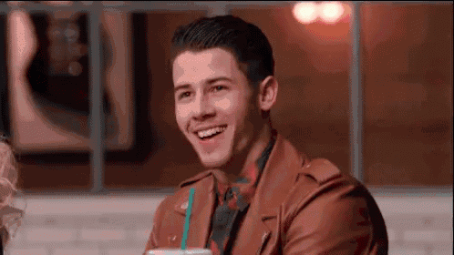 a man in a brown leather jacket is smiling while holding a cup of coffee .