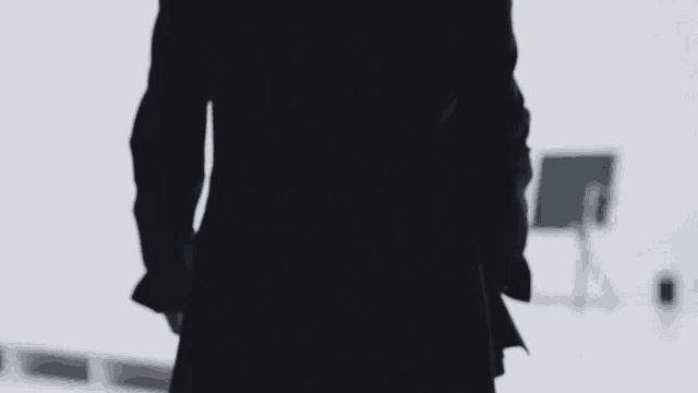 a woman in a suit is standing in a room with a chair and umbrella