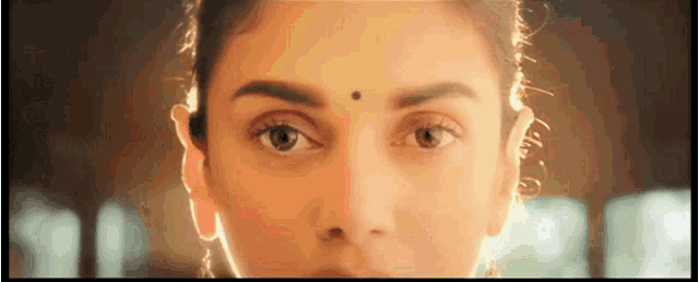 a close up of a woman 's face with a black spot on her forehead .