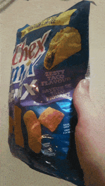 a person is holding a bag of chex mix taco flavour chips