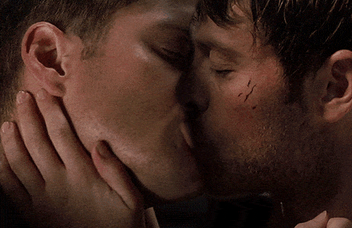 a close up of two men kissing with one having a scar on his forehead