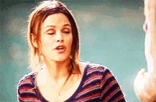 a woman in a striped shirt is talking to a man in a room .