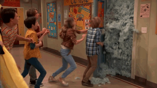 a group of kids are playing in a hallway with a bulletin board that says ' california ' on it