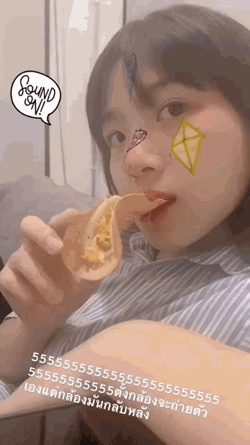 a girl with stickers on her face is eating a taco